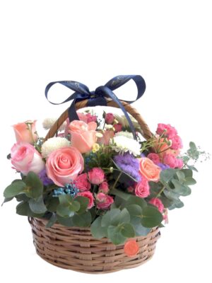 Arreglo de flores naturales con rosas, gerberas, mini rosas, bombones, gypsophila, eucalipto y follaje en una canasta.