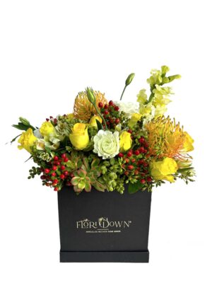 Arreglo de flores naturales con rosas amarillas, proteas e hipericum en caja de color negro.