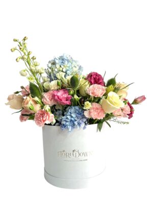 Arreglo de flores naturales con rosas, lisianthus, hortensias y mini rosas en base blanca.